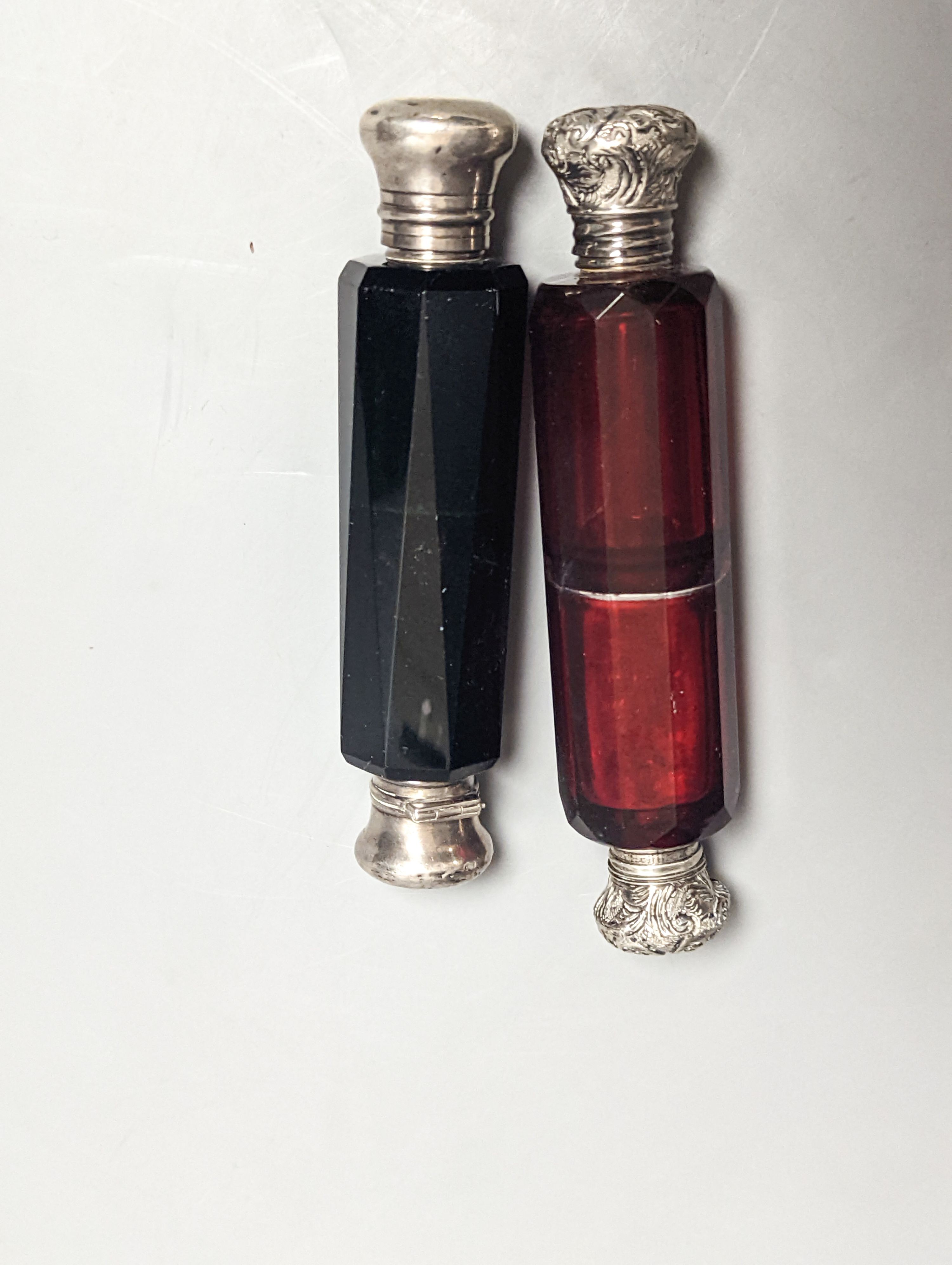 Two Victorian white metal mounted green or ruby glass double ended scent bottles, largest 13cm.